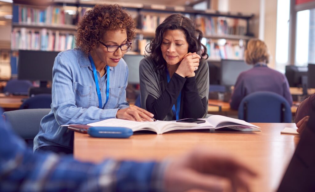 woman working with other woman in library